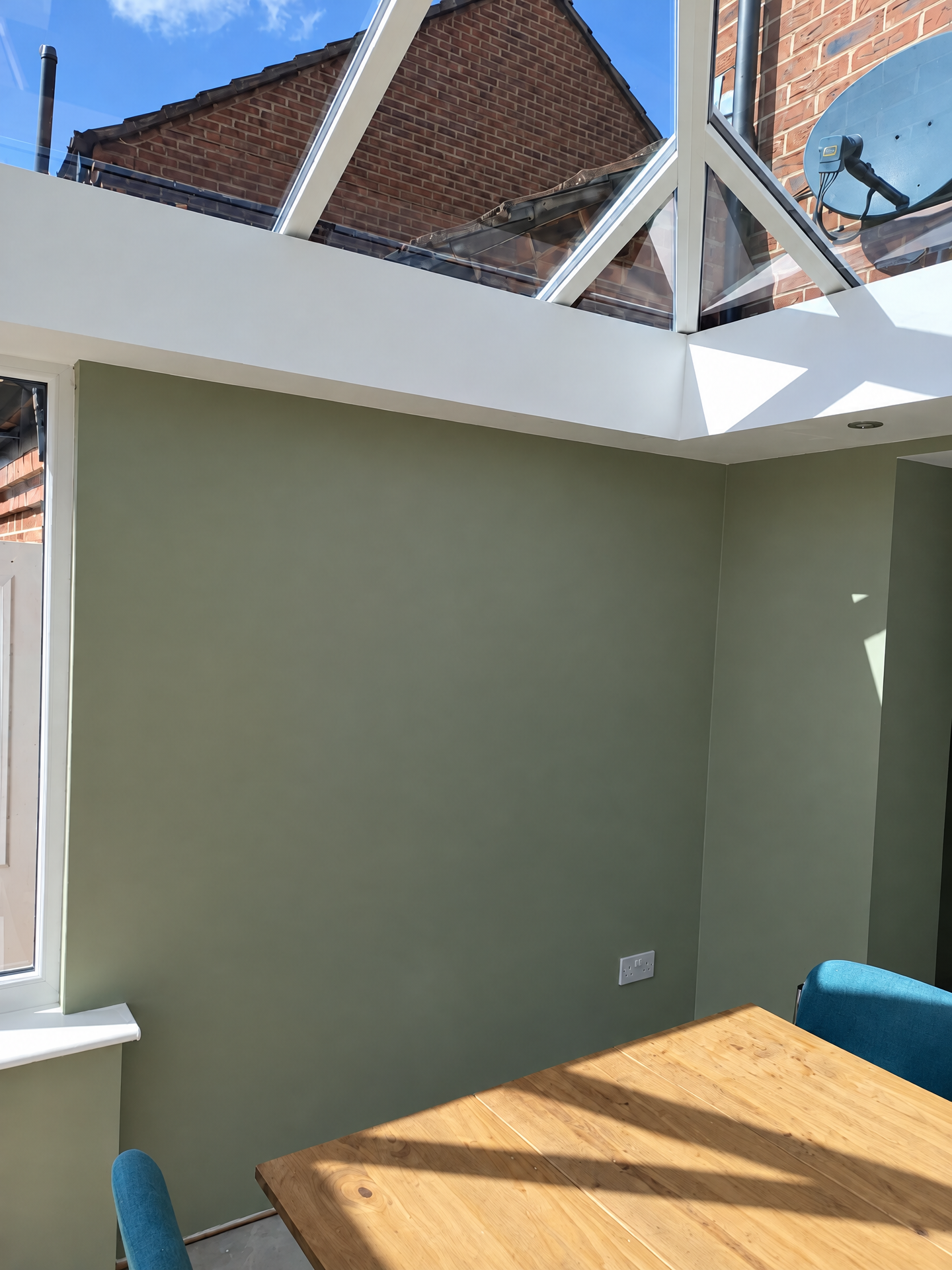 Freshly painted sage green room under a roof lantern