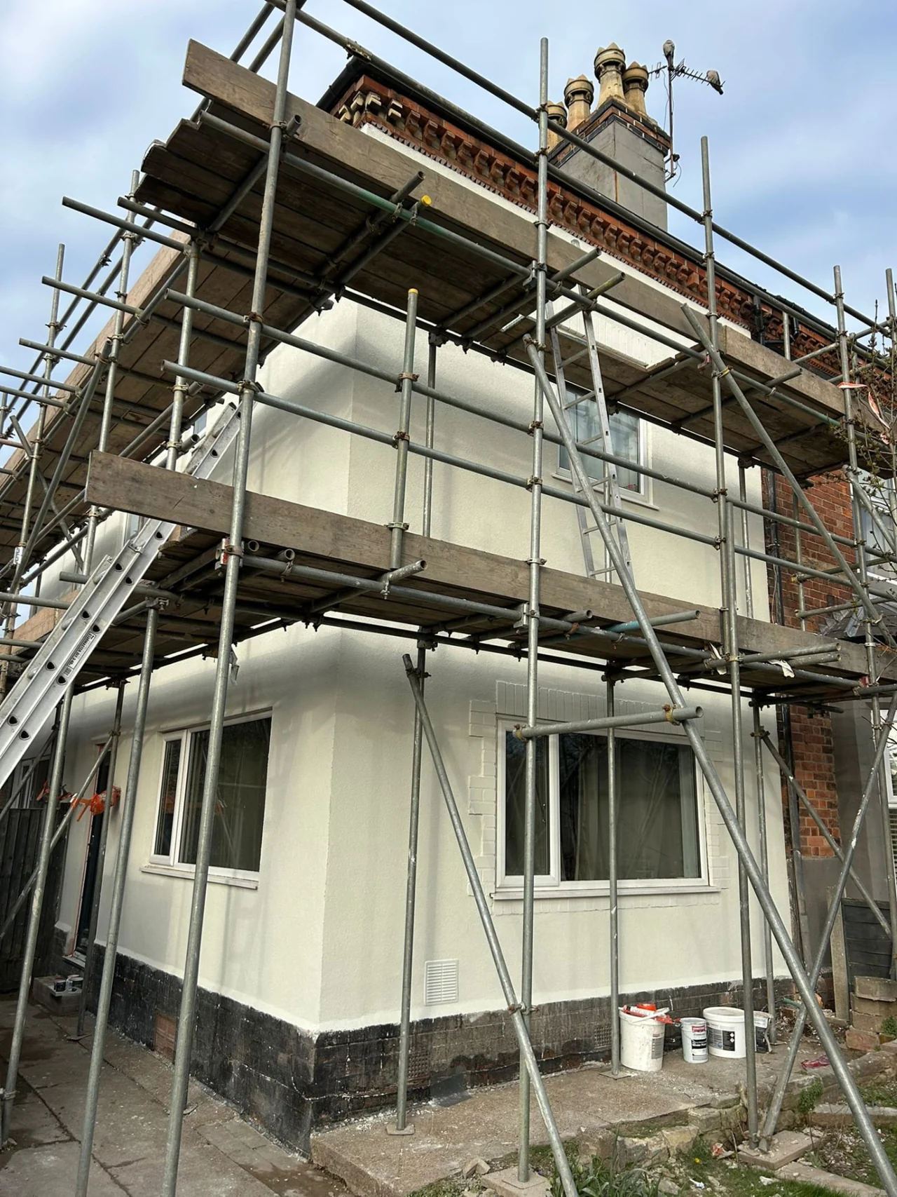 House facade with pale external render behind scaffolding
