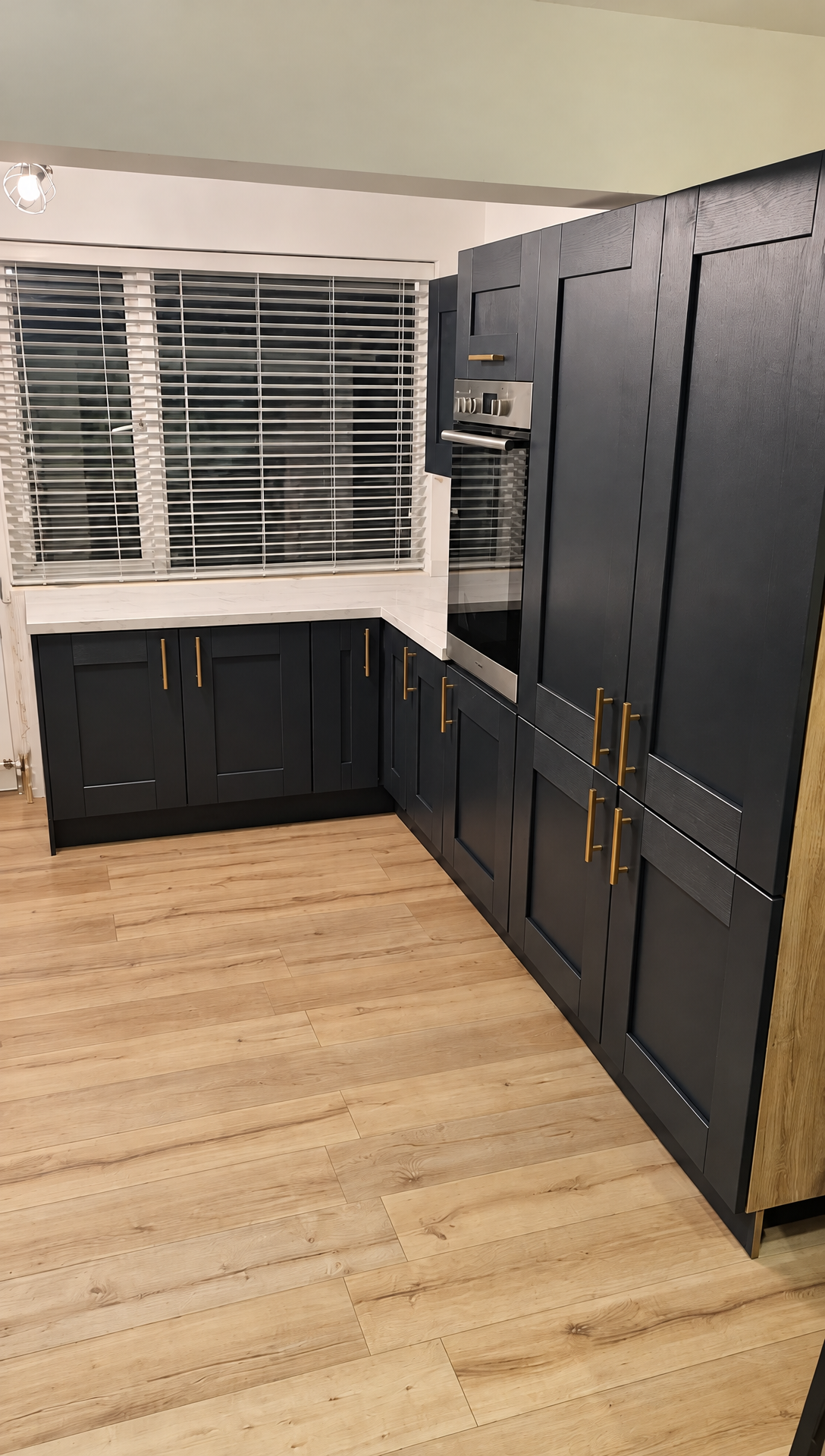 Dark shaker kitchen with brass handles and wood-effect flooring