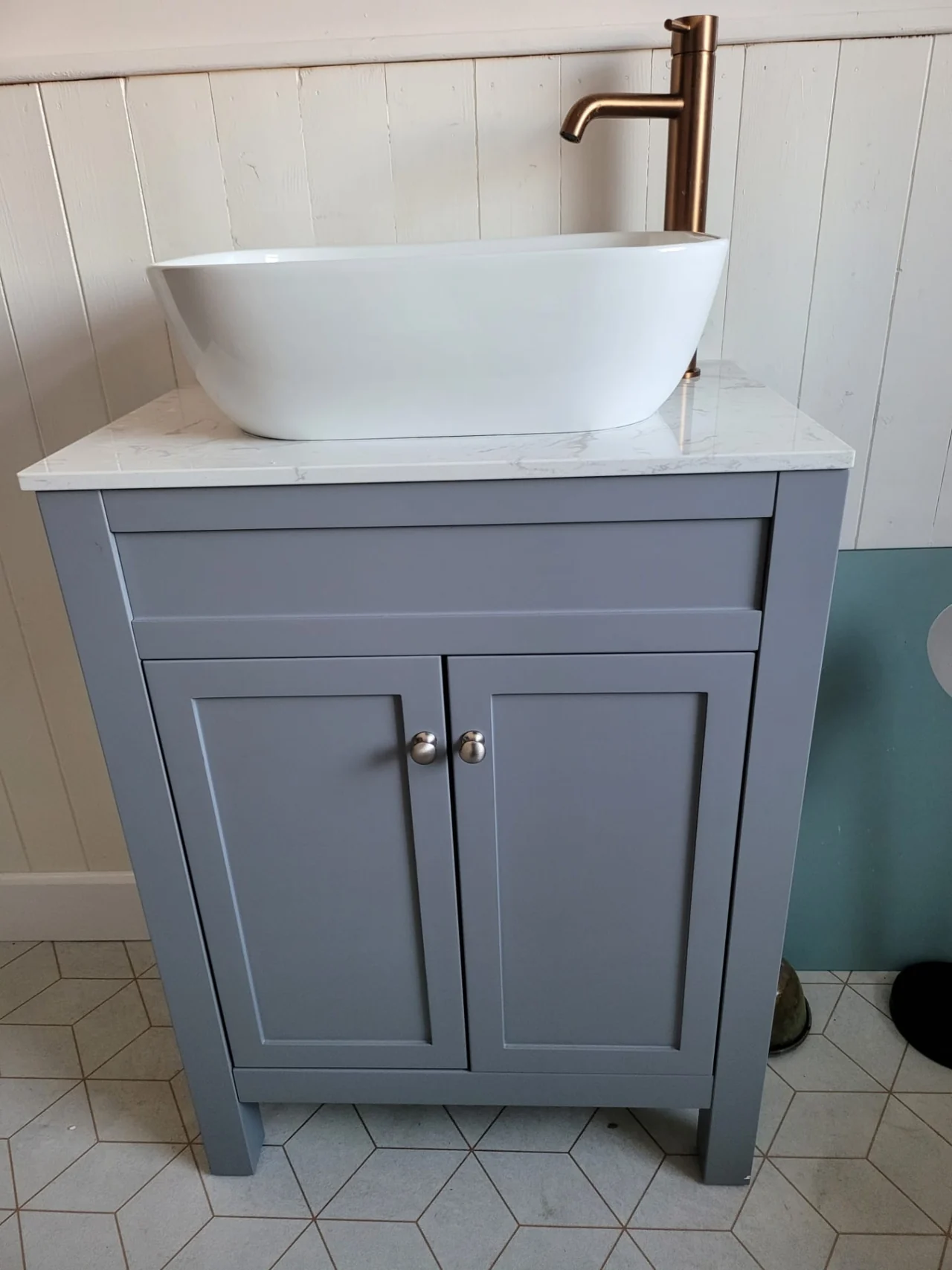 Grey bathroom vanity unit with a white basin and brass tap